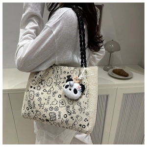 Détail du sac cabas en tricot avec textes gribouillés et pendentif panda en peluche