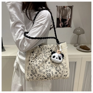 Detail of woven tote bag with cartoon graffiti and a panda plush charm in a cozy room