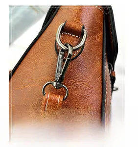 Macro detail of vintage brown leather bag featuring gunmetal swivel hook and white stitching