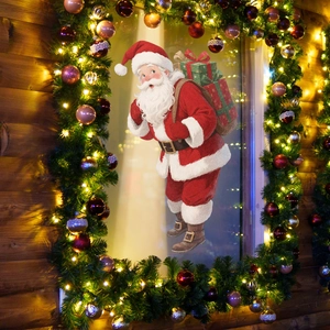 Detail of vintage Santa Claus window cling with gift bag on glass among festive garlands