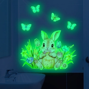 Luminous wall stickers showing glowing green rabbit and butterflies in dark bathroom