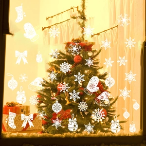 Close-up of white snowflake and bell static window decals in a warm Christmas home setting