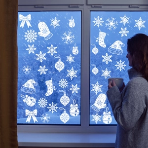 White Christmas window decals showing snowflakes and bells for cozy holiday home decor