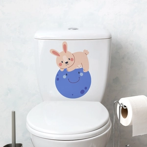 Close-up of cute cartoon rabbit and smiling moon decal on white ceramic toilet tank