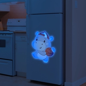 Glow-in-the-dark hippo sticker with basketball glowing in blue light on white surface