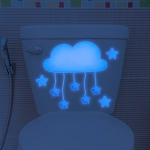 Luminous cloud and stars wall decals glowing blue on a bathroom wall in the dark