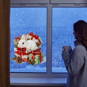 Detailed view of Christmas rabbit window sticker with gift boxes on a snowy night glass