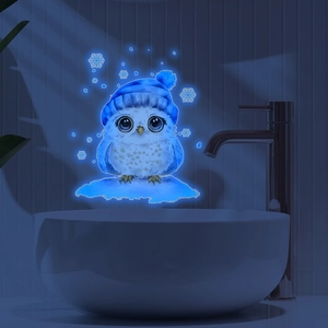 Luminous blue owl wall sticker with snowflakes glowing on a dark wall background