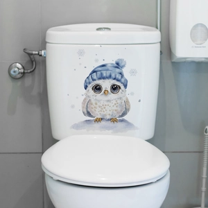Close-up of cute owl toilet sticker with blue hat and snowflakes on white water tank