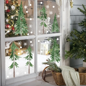 Detail of watercolor Christmas tree window stickers with snowflakes on a glass window