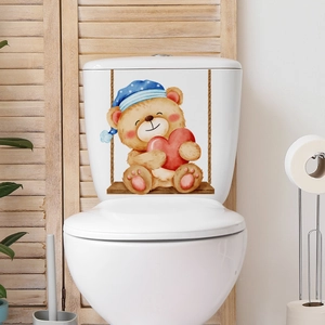 Detailed view of cartoon bear on swing wall sticker applied to a white toilet tank