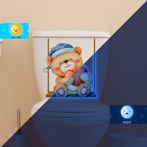 Luminous toilet sticker showing cartoon bear glowing blue in dark and daytime effect