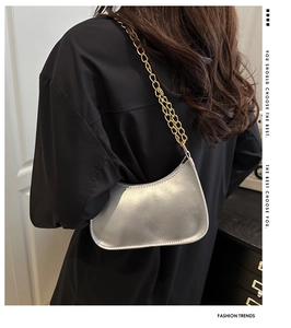 Detail of silver crescent hobo bag with chunky gold chain strap on a model shoulder