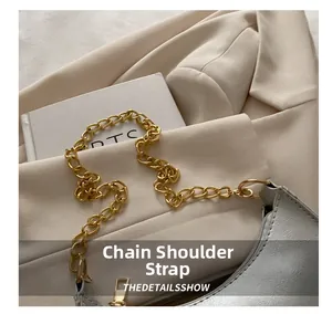 Close-up of shiny silver moon bag featuring a thick gold metal chain shoulder strap