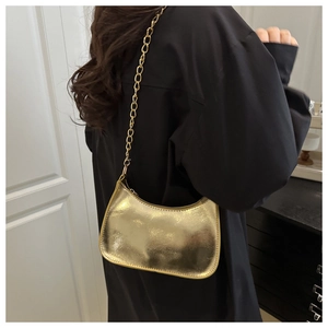 Detailed view of metallic gold hobo bag with chain strap styled on model's shoulder