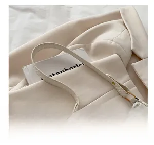 Detail of woven cream white shoulder bag featuring gold hardware and premium texture