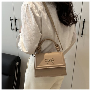 Detalle del bolso de cuero caqui con hebilla de lazo dorado y diseño de asa anudada