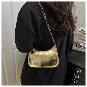 Detailed view of the metallic gold hobo bag with sleek chain strap on model's shoulder
