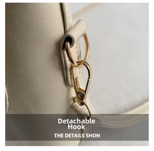 Détail d'un crochet amovible doré sur un grand sac cabas en cuir beige texturé