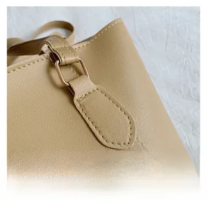 Détail de coutures blanches sur cuir grainé litchi avec boucles en métal doré
