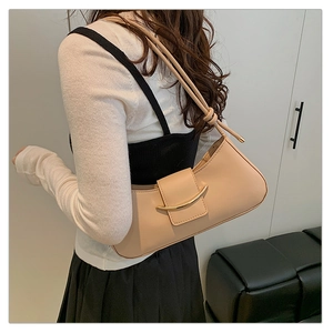 Detail of minimalist beige leather underarm bag with elegant gold curved buckle closure