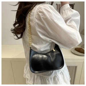 Close-up of black hobo bag with glossy finish and elegant gold chain shoulder strap