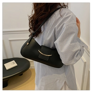 Close-up of minimalist black leather underarm bag with iconic gold crescent metal buckle