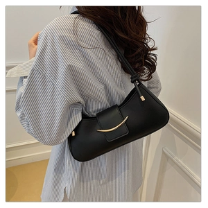 Detail of black underarm bag with gold metal buckle and knotted strap on model