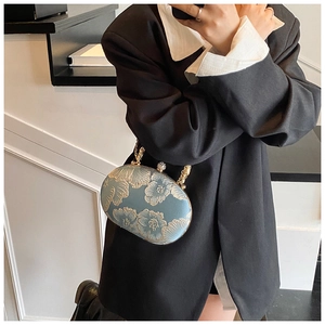 Detail of grey-blue chain handbag with gold floral embroidery and metal frame