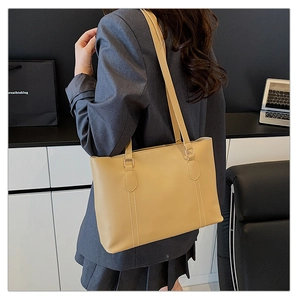 Vue détaillée du grand sac cabas en cuir beige avec surpiqûres blanches sur un mannequin