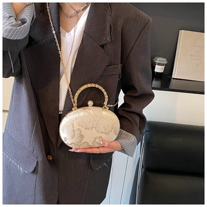 Detail of elegant beige embroidery evening bag with gold circular handle and chain strap