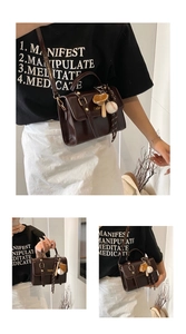 Detail showing deep brown glossy square crossbody bag with sports charms and gold buckle