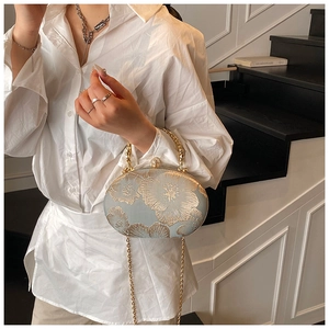 Detail of floral embroidery on light blue evening bag with pearl clasp and metal handle
