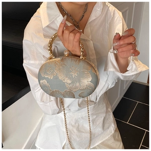 Detail of vintage evening clutch with intricate floral embroidery and gold metal handle
