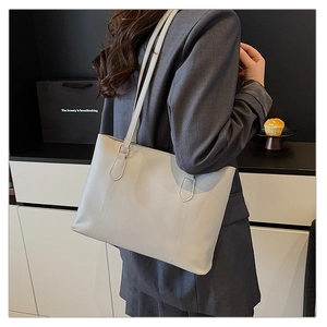 Détail du sac cabas minimaliste gris clair avec coutures verticales et longue bandoulière