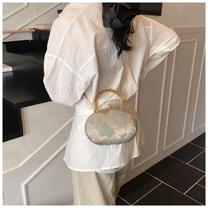 Detail of elegant floral embroidery on a grey satin evening bag with gold chain strap