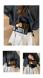 Detail of black glossy handbag with fashion charms including baseball and cookie pendants