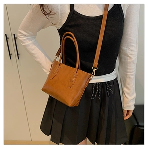 Grand sac cabas marron vintage avec poignées et bandoulière porté par un mannequin