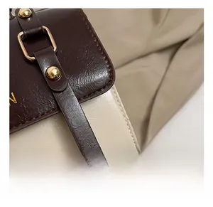 Close-up of vintage faux leather crossbody bag with contrast stitching and gold hardware