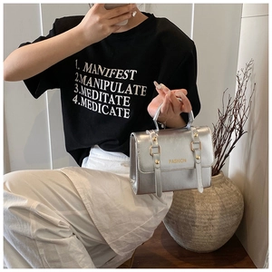 Detail of silver metallic handbag featuring fashion lettering and gold stud accents