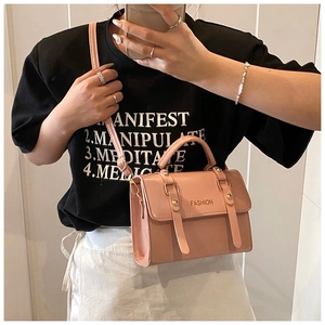Detail view of pink crossbody bag with metal accents and Fashion lettering worn by model