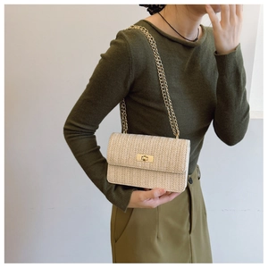 Detail of a beige woven chain bag with gold metal lock on a green outfit