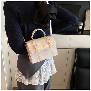 Detalle del bolso cuadrado crema con logo FASHION dorado y textura de cuero brillante