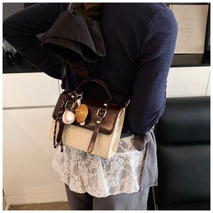 Close-up of retro color-block handbag with baseball charm and elegant crossbody strap
