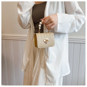 Detailed shot of straw woven square bag with heart lock and elegant pearl top handle