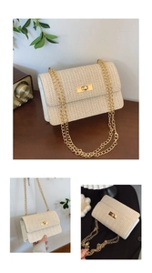 Detail of woven straw shoulder bag with gold metal clasp and chain strap on wooden table