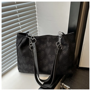 Close-up of black jacquard tote bag with heart pattern and silver metal chain detail