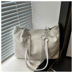 Detailed view of textured 3D heart jacquard fabric on a white tote bag with chain strap