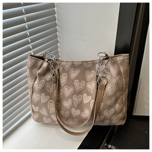 Close-up of heart-patterned jacquard tote bag with silver chain and leather strap details