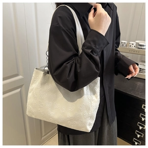Detail of white tote bag with embossed heart texture and stylish wide shoulder strap
